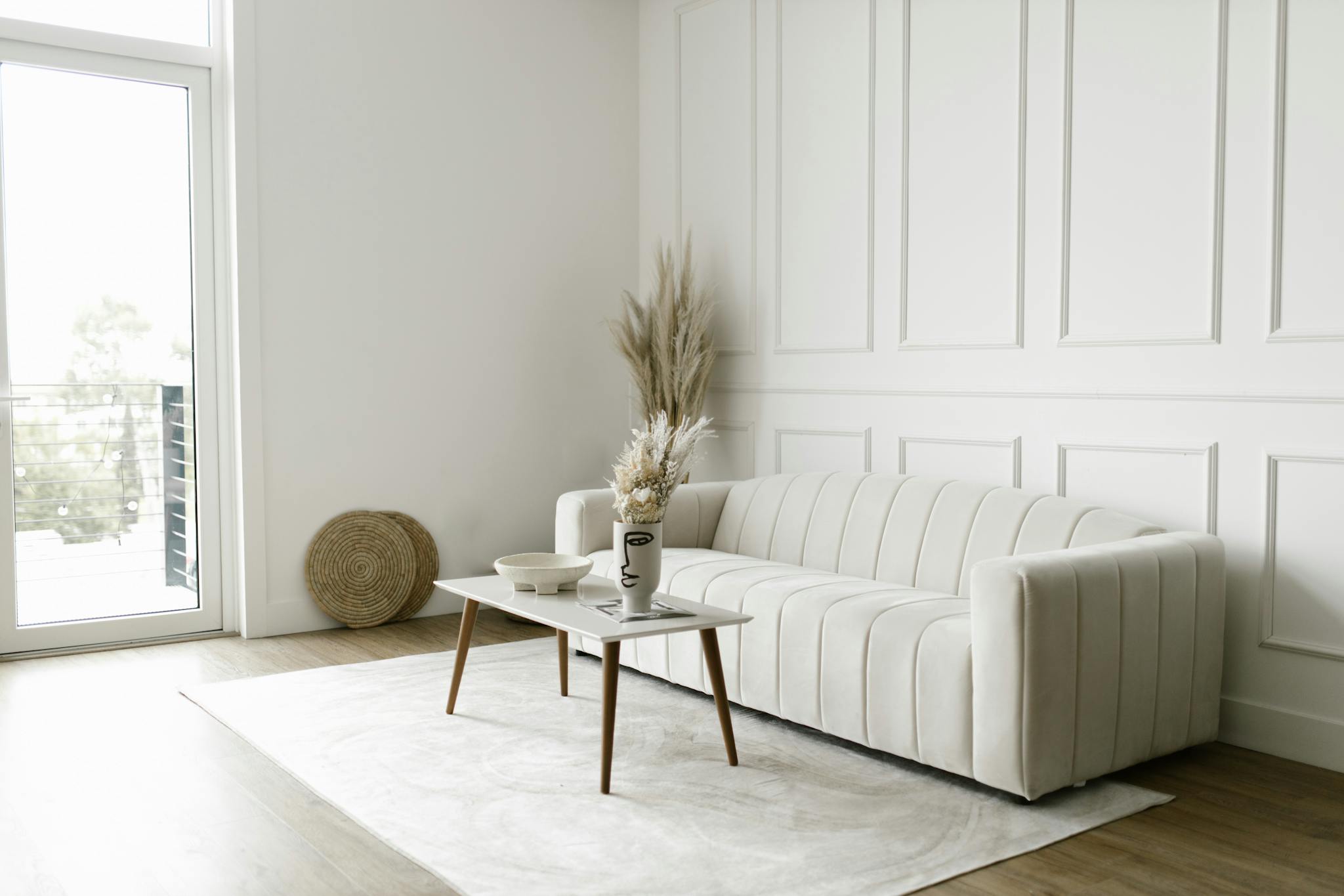 Elegant and simple living room featuring minimalist furniture, a white sofa, and decor elements.