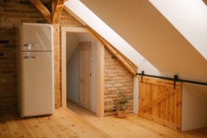 Rustic attic loft with wooden beams, vintage fridge, and warm ambiance.